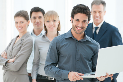 Happy business man holding a modern laptop computer with his team in background
